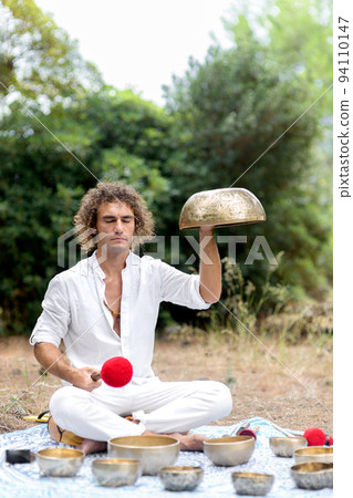A man playing on a singing tibetian bowl for relaxation and meditation. Buddhist healing practices and sound therapy A man playing on a singing tibetian bowl for relaxation and meditation. Buddhist healing practices and sound therapy 94110147