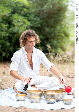 A man playing on a singing tibetian bowl for relaxation and meditation. Buddhist healing practices and sound therapy 94110154