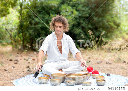 A man playing on a singing tibetian bowl for relaxation and meditation. Buddhist healing practices and sound therapy A man playing on a singing tibetian bowl for relaxation and meditation. Buddhist healing practices and sound therapy 94110155