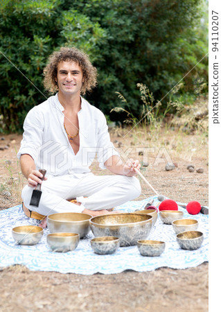 A man playing on a singing tibetian bowl for relaxation and meditation. Buddhist healing practices and sound therapy A man playing on a singing tibetian bowl for relaxation and meditation. Buddhist healing practices and sound therapy 94110207