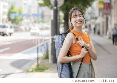 A young woman holding a yoga mat 94110544
