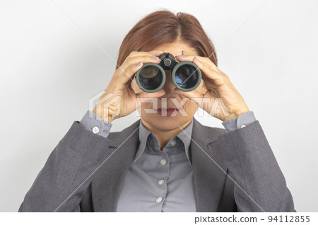 Business woman in suit looking through binoculars 94112855
