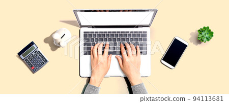 Woman using a laptop computer with a piggy bank Woman using a laptop computer with a piggy bank 94113681