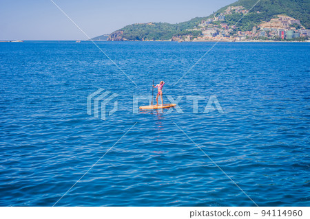 Young women Having Fun Stand Up Paddling in blue water sea in Montenegro. SUP. girl Training on Paddle Board near the rocks Portrait of a disgruntled girl sitting at a cafe table 94114960