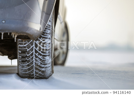 Close up of a car tire parked on snowy road on winter day. Transportation and safety concept. Close up of a car tire parked on snowy road on winter day. Transportation and safety concept. 94116140
