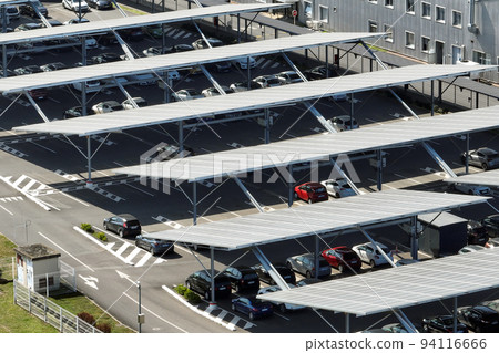 Aerial view of solar panels installed over parking lot with parked cars for effective generation of clean energy 94116666