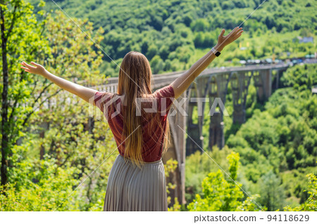 Montenegro. Woman tourist in background of Dzhurdzhevich Bridge Over The River Tara. Travel around Montenegro concept. Sights of Montenegro Portrait of a disgruntled girl sitting at a cafe table 94118629