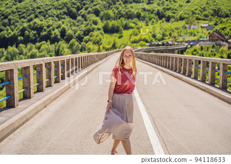 Montenegro. Woman tourist in background of Dzhurdzhevich Bridge Over The River Tara. Travel around Montenegro concept. Sights of Montenegro Portrait of a disgruntled girl sitting at a cafe table 94118633