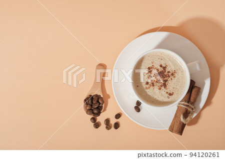 cinnamon coffee cappuccino in white classic cup on beige background. top view of hot autumn and winter spicy coffee. seasonal hot drinks 94120261