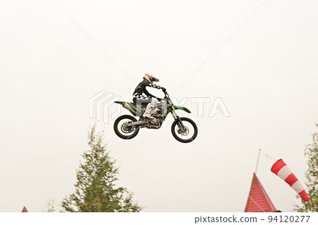 Freestyle motocross. Biker rider doing a jumpin the air. Perfoming acrobatic stunt flying. Fmx motocycles. protective uniform and helmet. 94120277