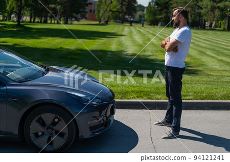 Caucasian man connect charger to electric car. Caucasian man connect charger to electric car. 94121241