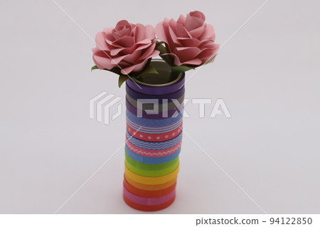 A cylinder made by stacking colorful tapes decorated with origami roses. A cylinder made by stacking colorful tapes decorated with origami roses. 94122850