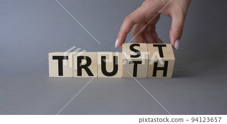 Trust and Truth symbol. Businessman hand Turnes cubes and changes word Truth to Trust. Beautiful grey background. Business and Trust and Truth concept. Copy space Trust and Truth symbol. Businessman hand Turnes cubes and changes word Truth to Trust. Beautiful grey background. Business and Trust and Truth concept. Copy space 94123657