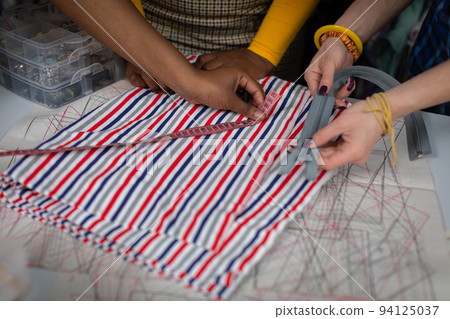 Clothing designers measure tailor's fabric on a tailor's table. Clothing designers measure tailor's fabric on a tailor's table. 94125037