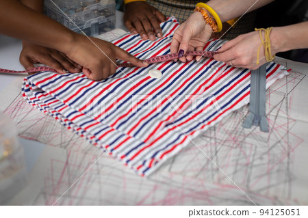 With his finger, he points to a button that lies on the fabric. Tailor's workshop. With his finger, he points to a button that lies on the fabric. Tailor's workshop. 94125051