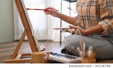 Happy young woman painting picture with watercolor at cozy home. Art, creative hobby and leisure activity concept Happy young woman painting picture with watercolor at cozy home. Art, creative hobby and leisure activity concept 94126786