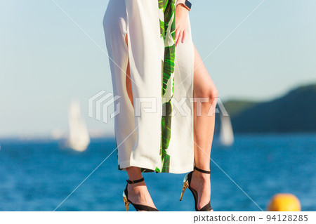 Woman feet in high heels shoes on sea pier Woman feet in high heels shoes on sea pier 94128285