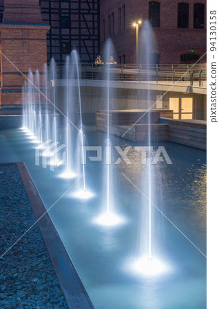 Vertical view on row of white water fountains at dusk. 94130158