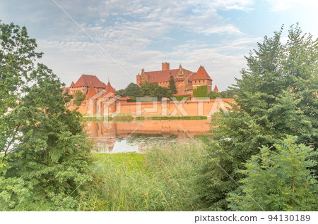 View between trees on Malbork Medieval Teutonic Order Castle. 94130189