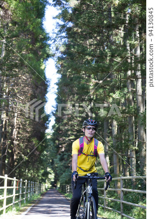 A cyclist running through a cedar forest 94130845