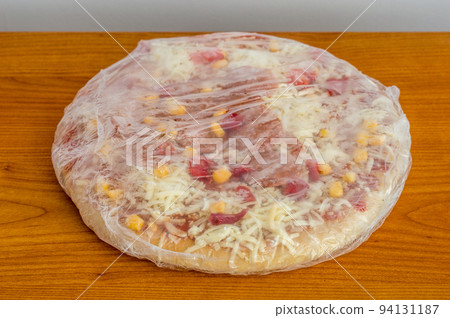 Frozen pizza in foil with pepperoni. Frozen pizza in foil with pepperoni. 94131187