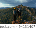 Travelers on the background of autumn mountains. Mountain tourism. Walking tour of the autumn mountains. A trip to the mountains with a backpack. A couple in love against the background of mountains 94131407