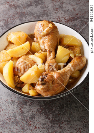 Chicken drumsticks stewed with potatoes in a spicy sweet sauce Indonesian food close-up. Vertical 94131625
