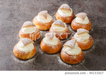 sweet buns Semla or semlor with cardamom, filled with almond paste and whipped cream closeup. Horizontal 94131927