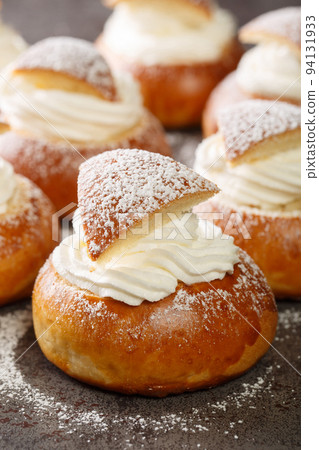 Traditional winter sweet Semla semlor or fastlagsbulle flavored with cardamom, filled with almond paste and whipped cream closeup. Vertical 94131933