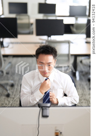 商人一邊看電腦顯示器一邊調整領帶 94132418