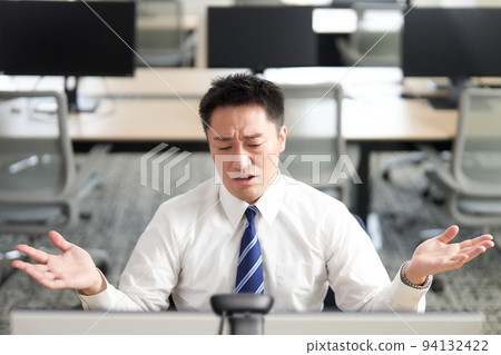 Businessman during a video call raising his hands and wrinkling his eyebrows Businessman during a video call raising his hands and wrinkling his eyebrows 94132422