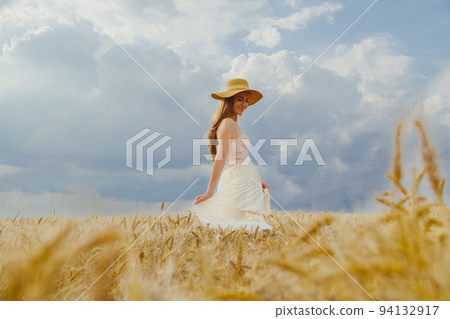 Woman in rural dress and hat dancing alone in wheat field 94132917