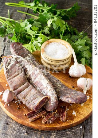 Beef jerky smoked sausage sudzhuk with spices and garlic is served on a cutting board. Copy space for text. Beef jerky smoked sausage sudzhuk with spices and garlic is served on a cutting board. Copy space for text. 94133203