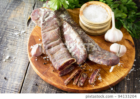 Beef jerky smoked sausage sudzhuk with spices and garlic is served on a cutting board. Copy space for text. 94133204