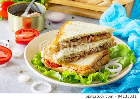Double sandwich with canned tuna and feta cheese served with lettuce leaves on a background of gray stone. Double sandwich with canned tuna and feta cheese served with lettuce leaves on a background of gray stone. 94133331