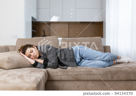 Young woman sleeping on sofa at home, tired after work Young woman sleeping on sofa at home, tired after work 94134370
