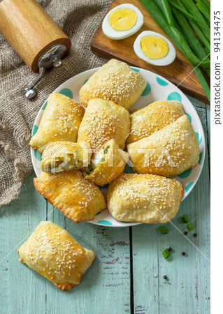 Ukrainian or Russian cuisine. Baked small pies with egg and green onions, spring vitamin baked goods. Top view flat lay. Copy space. 94134475