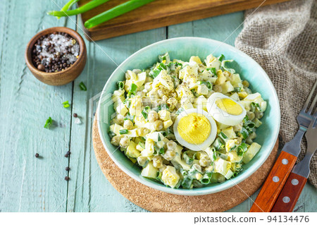 Spring salad with egg, green peas and green onions in a bowl on a rustic table. 94134476