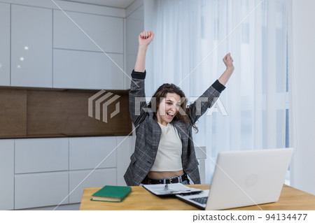 Young beautiful girl student at home online with laptop video call rejoices, laughs, learned that she passed the exams, entered the university 94134477
