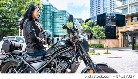 A female rider touring Yokohama on a large cruiser bike A female rider touring Yokohama on a large cruiser bike 94137327