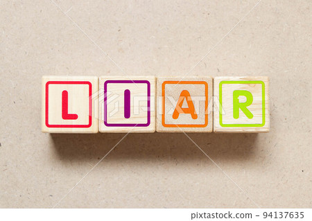 Color letter block in word liar on wood background 94137635