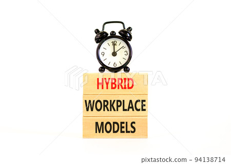 Hybrid workplace models symbol. Concept words Hybrid workplace models on wooden blocks. Black alarm clock. Beautiful white table white background. Business hybrid workplace models quote concept. Copy 94138714