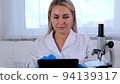 Woman scientist research chemist in a medical suit and protective gloves with a tablet computer and 94139317