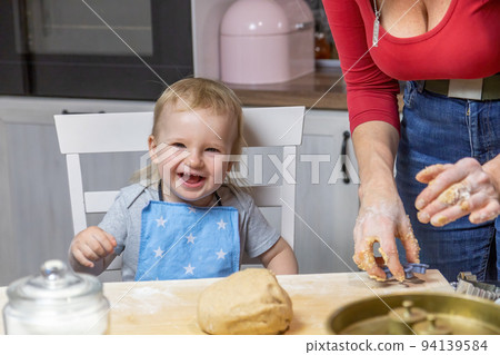 Laughing little child boy is helpful in baking cookies Laughing little child boy is helpful in baking cookies 94139584