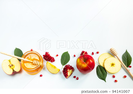 Concept of traditional Jewish holiday of Rosh Hashanah. New Year. Pomegranates, honey and apples on white background. Place for your text. 94141007
