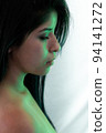 Portrait photo, Latin woman with black hair and serious look, posing side to left with white background. 94141272