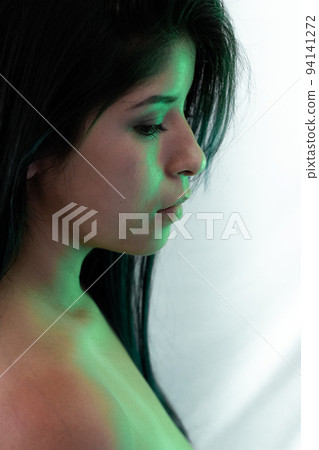 Portrait photo, Latin woman with black hair and serious look, posing side to left with white background. 94141272