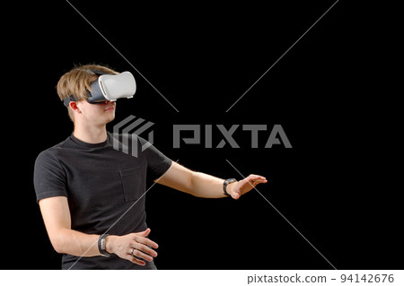 Young man wearing virtual reality VR glasses, goggles isolated on black background. Inside A Metaverse 94142676
