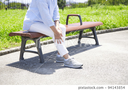 Middle-aged woman who feels knee pain while walking Middle-aged woman who feels knee pain while walking 94143854