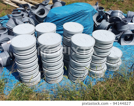 Manholes and adjusters piled up at a construction site 94144827